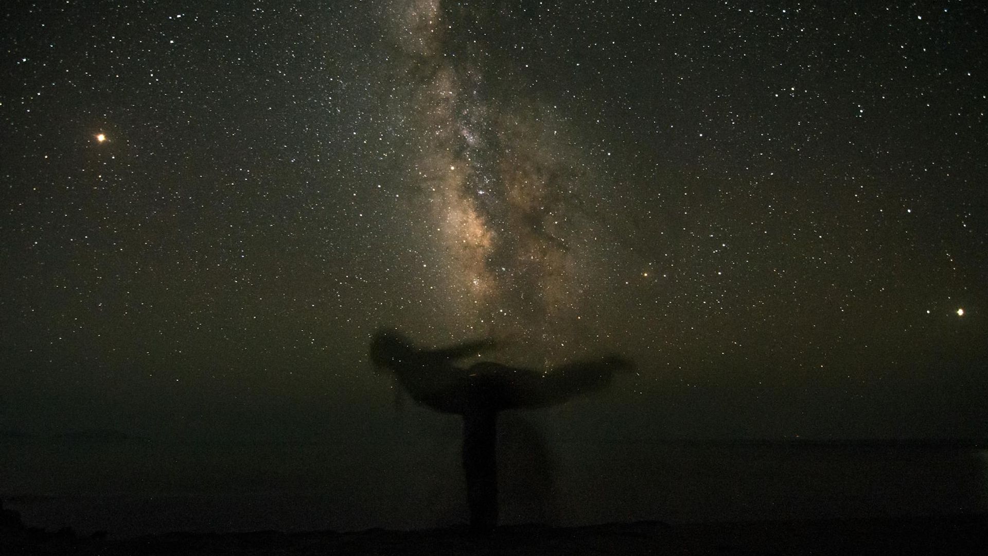 Calm silhouette of a person in a yoga pose against a dark, serene background.